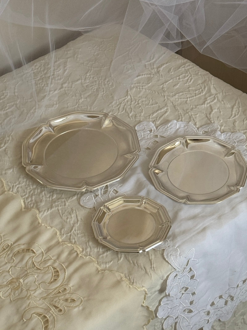 three silver plated round trays on a white fabric