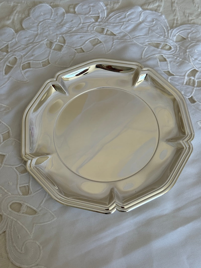 Silver decorative plate on a textured white surface