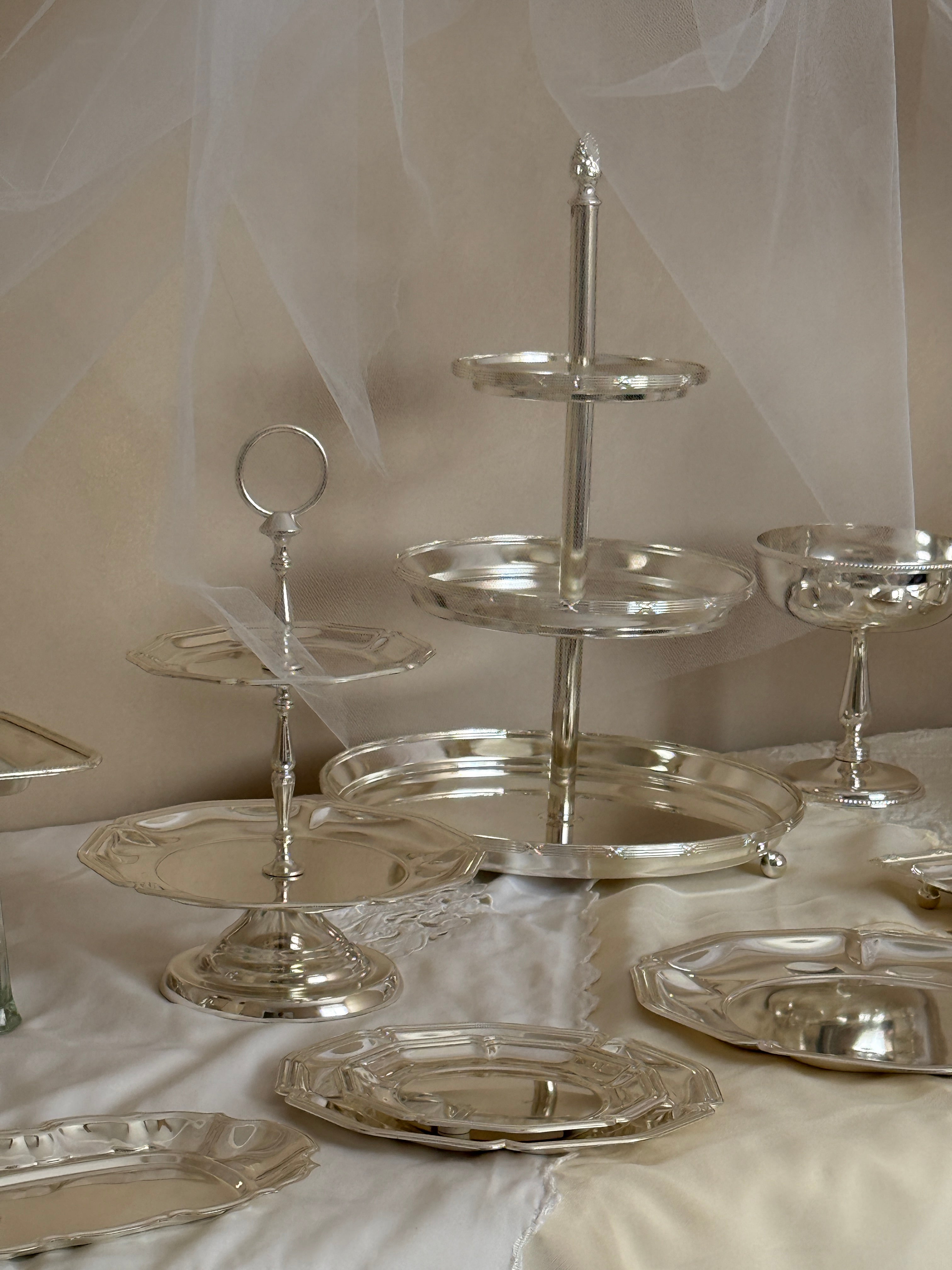 Close-up of a silver cake stand with decorative elements on a white background