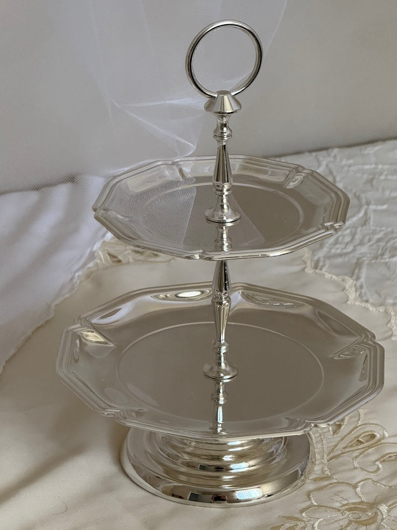 Silver two-tiered stand on a white fabric background